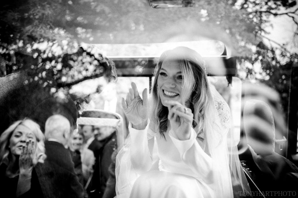 Bride Anna waves through the glass of the Land Rover