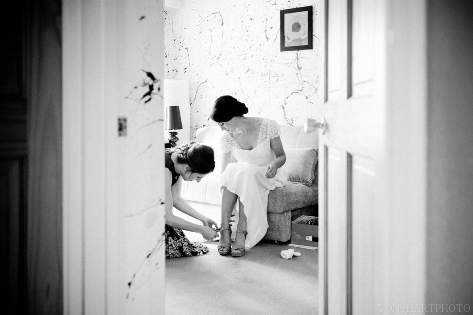 Liz's bridesmaid helps her into her shoes