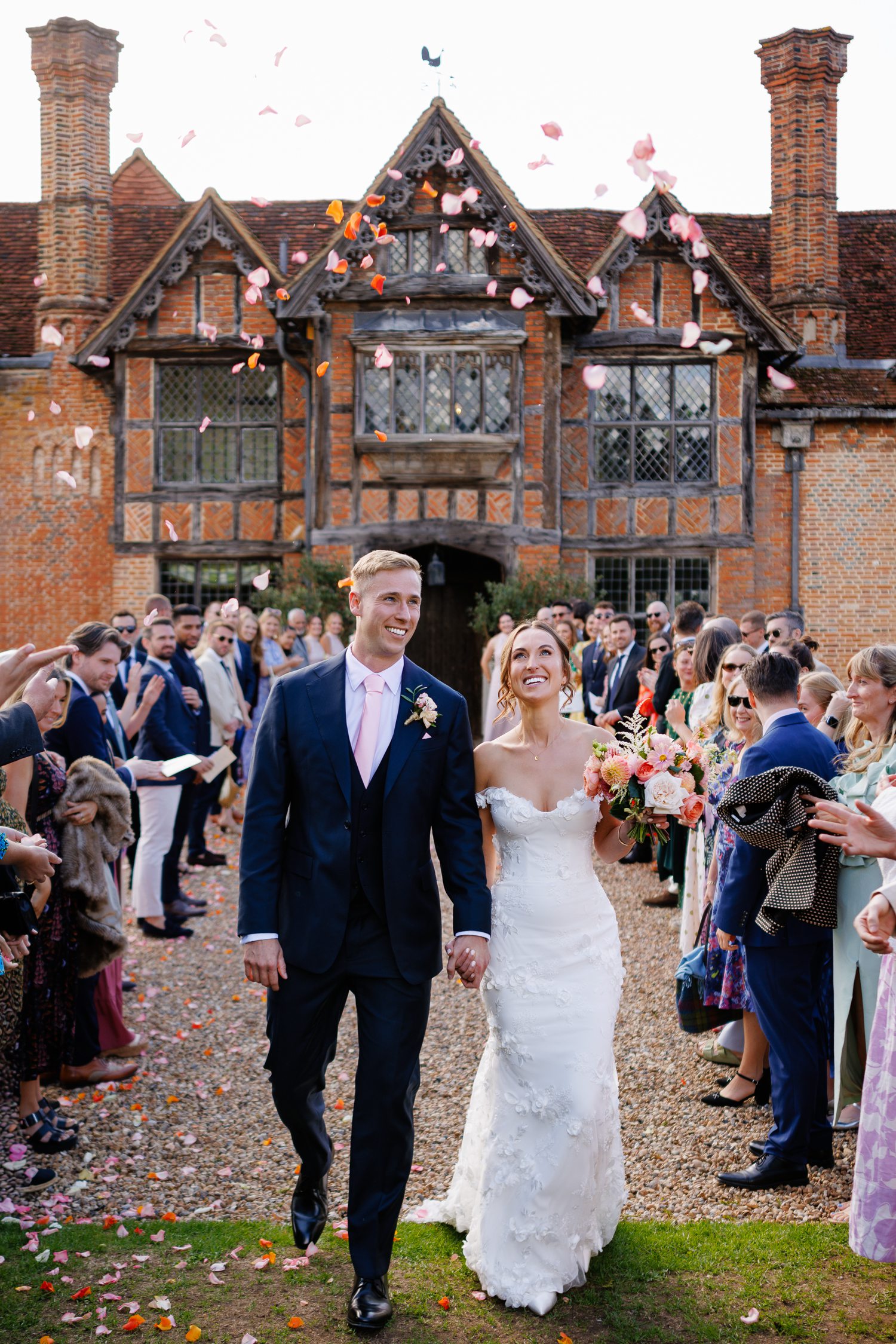 Bride and groom walking through confetti outside Dorney Court after their wedding ceremony.