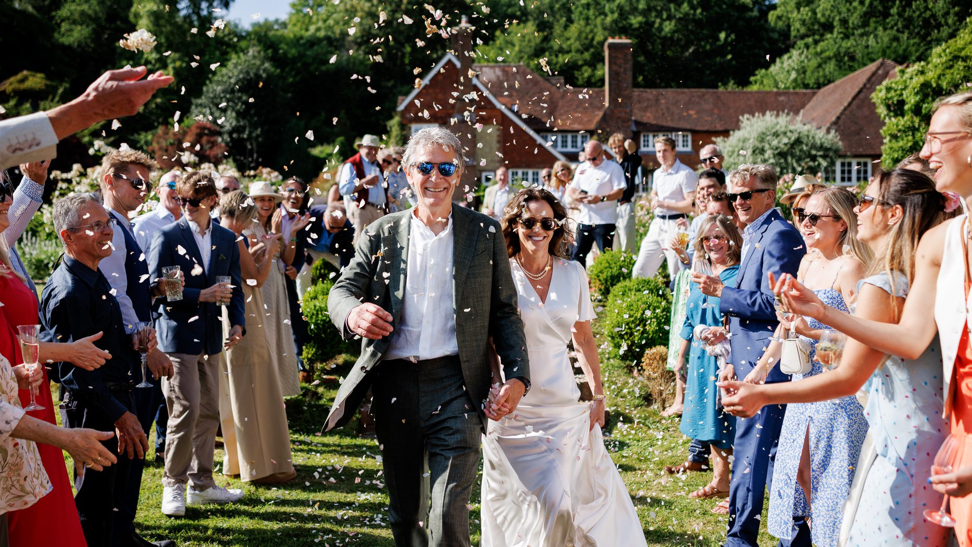 A bride & groom showered with confetti during their summer private garden wedding in the Surrey Hills.